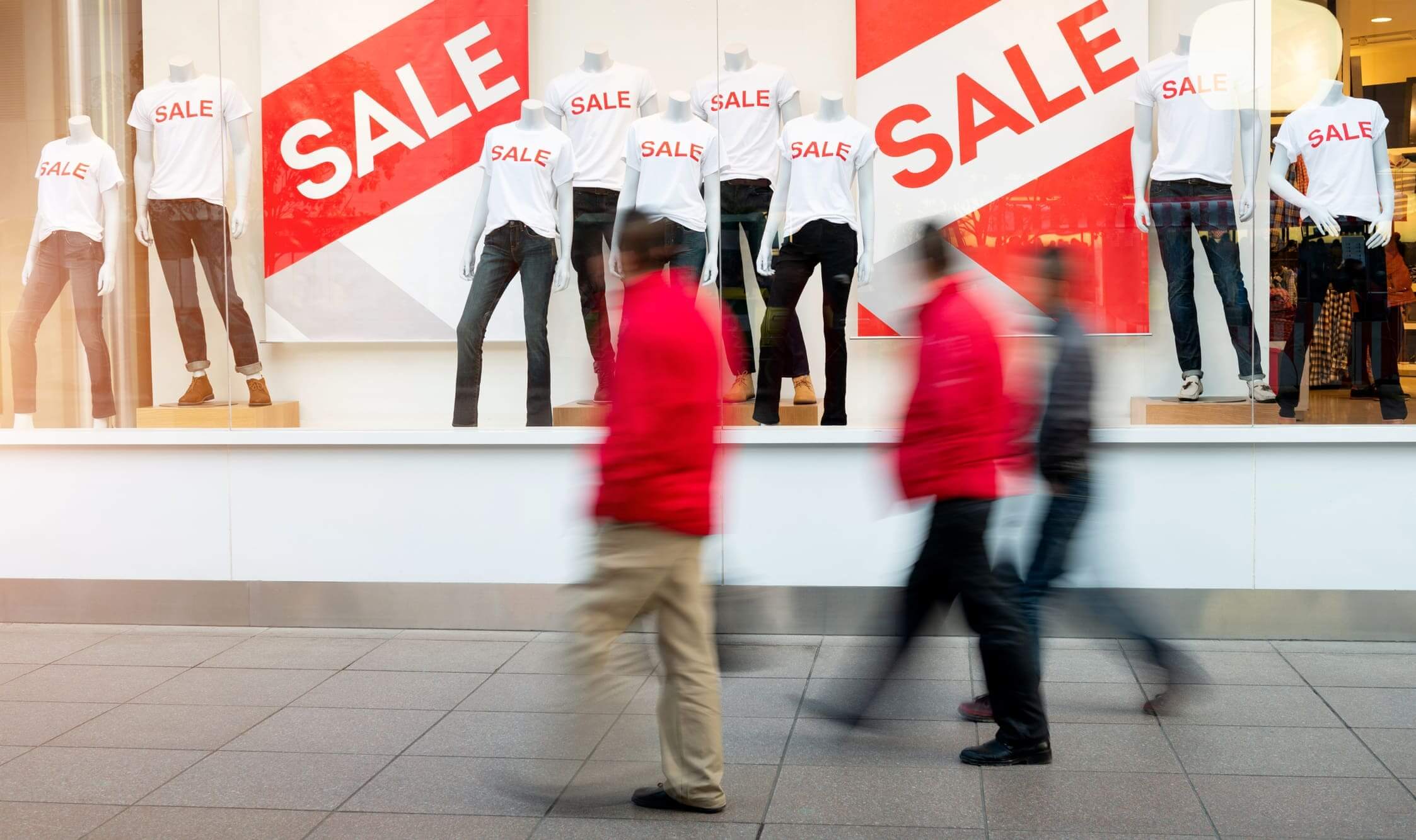 Storefront with mannequins displaying sale signs.