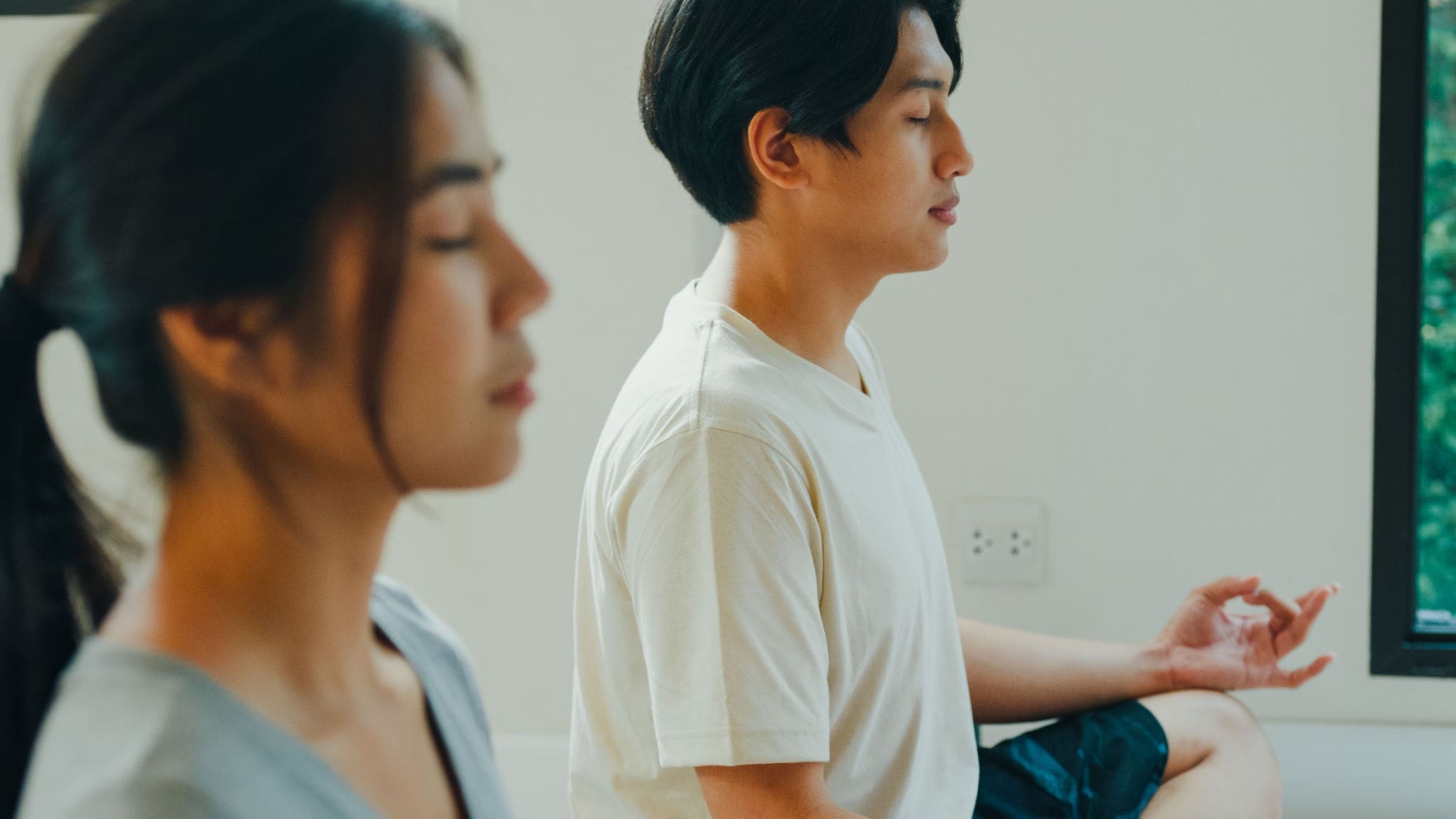 Two people meditating peacefully indoors.
