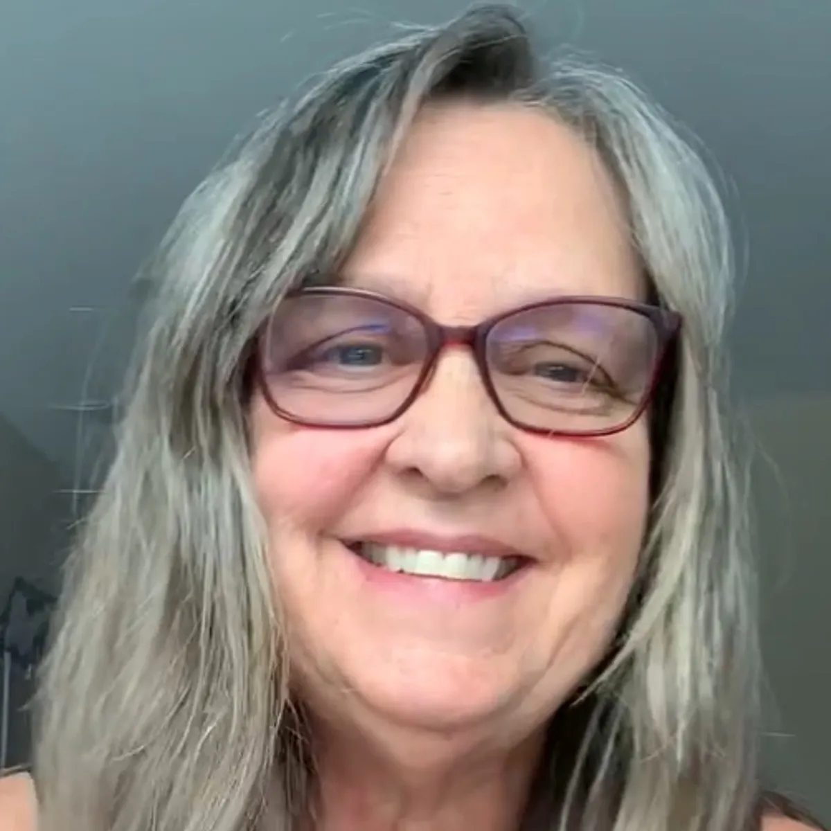 Smiling woman with glasses and gray hair.