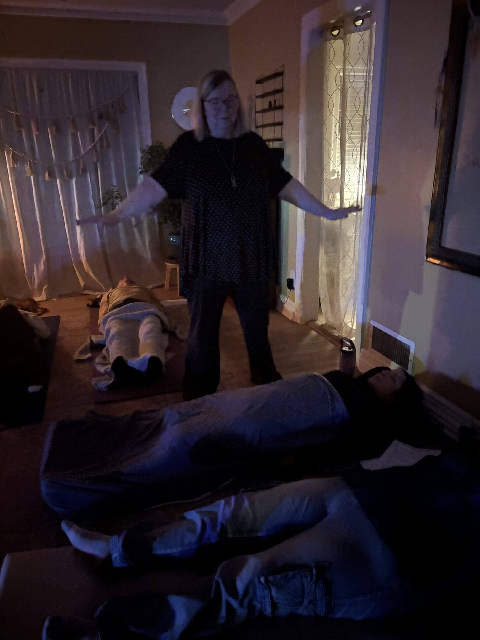 Woman meditating with people lying down.